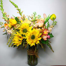 Bouquet of yellow sunflowers and pastel flowers in a glass vase