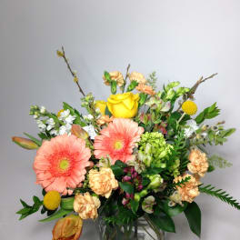 Mixed bouquet with pink gerbera daisies and yellow roses in a glass vase