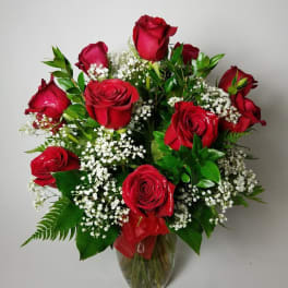Red roses arranged in a clear glass vase with white filler flowers