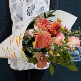 Bouquet of peach and pink flowers wrapped in white paper