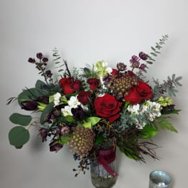 Bouquet of red roses and dark purple flowers in a glass vase