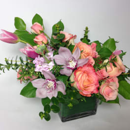Pink roses and lavender orchids in a square glass vase