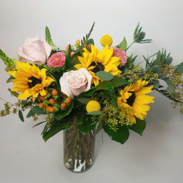 Bouquet of sunflowers and pale pink roses in a glass vase
