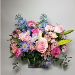 Pink and blue mixed flower arrangement in a clear glass vase