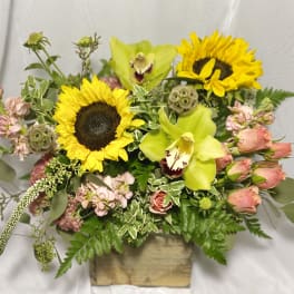 Mixed bouquet with sunflowers, green orchids, and pink roses in a wooden box