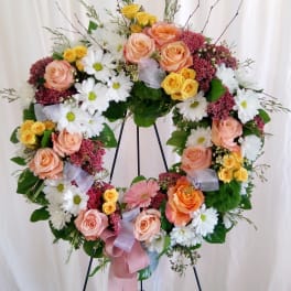 Heart-shaped floral wreath with roses and daisies on a stand