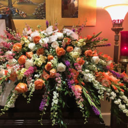 Large casket spray of orange and white roses with pink and purple flowers