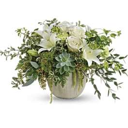 White roses and lilies in a low ceramic pot with trailing greenery