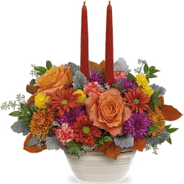Fall floral centerpiece with two red taper candles in a white bowl