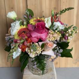 Mixed bouquet with pink roses, white blooms, and gerbera daisies in a glass vase