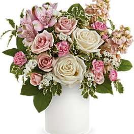 Pink and white roses in a white vase with mixed filler flowers