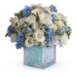 White and blue rose arrangement in a glass block vase
