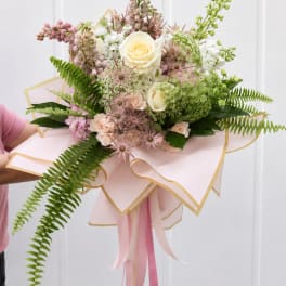Hand-tied bouquet of cream and blush flowers with pink ribbon wrap