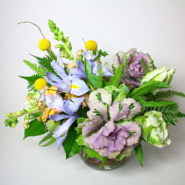 Mixed bouquet of lavender, purple, and yellow flowers in a glass vase