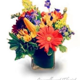 Colorful mixed flower bouquet in a square glass vase