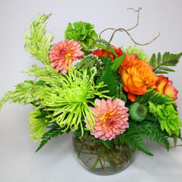 Bright mixed bouquet in a glass vase with orange, pink, and green blooms