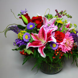 Colorful mixed bouquet with lilies, roses, and daisies in a glass vase