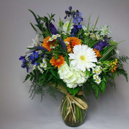 Mixed bouquet in a glass vase with white, orange, and blue flowers