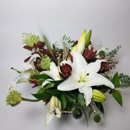 White lilies and burgundy flowers in a low arrangement