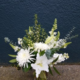 White floral arrangement in a glass vase with lilies and chrysanthemums