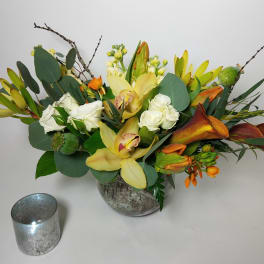 Mixed floral arrangement with yellow orchids, white roses, and orange callas in a vase