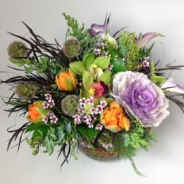 Mixed bouquet with purple cabbage roses and orange tulips in a low vase
