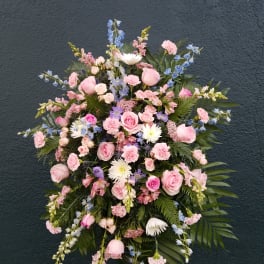 Large standing spray of pink and blue flowers on a dark wall