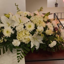 Large white floral arrangement with lilies, daisies, and hydrangeas