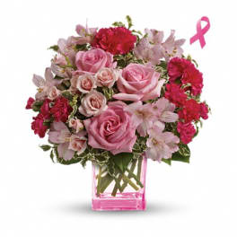 Pink roses and carnations in a pink glass vase with a ribbon