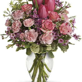 Pink tulips and roses arranged in a clear glass vase
