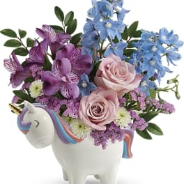 Bouquet of pink and blue flowers in a unicorn-shaped vase