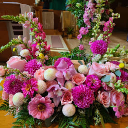 Pink floral arrangement with roses, dahlias, and snapdragons on a table