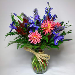 Colorful bouquet of pink, blue, and purple flowers in a glass vase