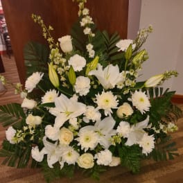Large white floral arrangement with lilies, roses, and daisies