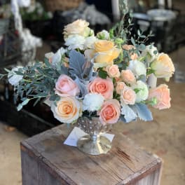 Pastel roses and white blooms arranged in a silver goblet vase