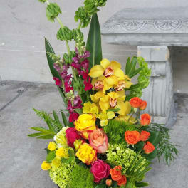 Tall mixed floral arrangement with yellow orchids, roses, and snapdragons