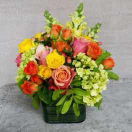 Colorful bouquet of roses and snapdragons in a green container