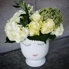 White floral arrangement in a white face vase