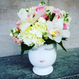 Pink and white flower arrangement in a white face vase
