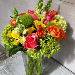 Colorful bouquet of roses and green blooms in a clear glass vase