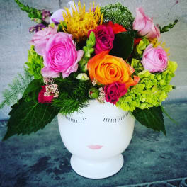 Colorful bouquet in a white face vase with roses and hydrangeas