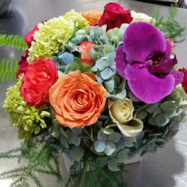 Colorful bouquet with roses, hydrangeas, and a purple orchid in a box