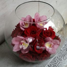 Red roses and pink orchids in a round glass bowl