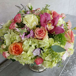 Bouquet of pink and peach roses with green hydrangeas and a magenta orchid