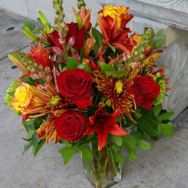 Mixed bouquet of red and yellow flowers in a clear glass vase
