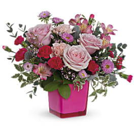 Pink and red mixed flower arrangement in a magenta vase
