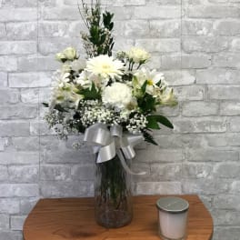 White floral arrangement in a glass vase with a silver ribbon