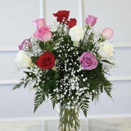 Bouquet of red, pink, purple, and white roses in a clear glass vase