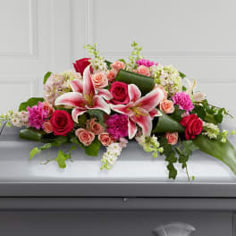 Casket spray with pink lilies, roses, and carnations