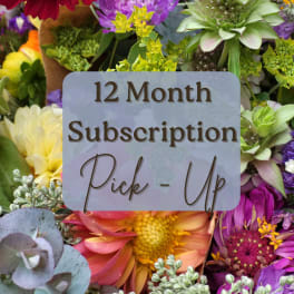 Mixed bouquet of colorful flowers with a "12 Month Subscription Pick-Up" sign